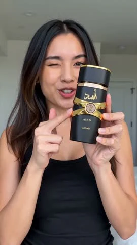 Moras AI video frame showing a presenter holding a black-and-gold fragrance bottle